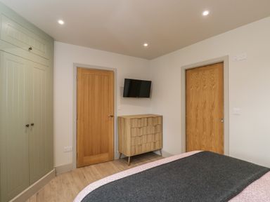 A bedroom featuring a bed, wardrobe, dresser, and television at Foxglove in Stratton Audley near Bicester
