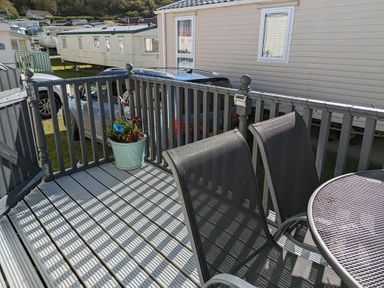 An outdoor deck with a table and chairs at Clarach Bay Holiday Village W18 Aberystwyth