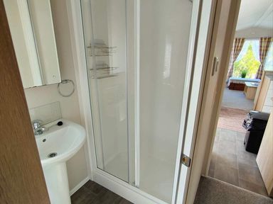 A bathroom with a shower and sink at Clarach Bay Holiday Village W18 Aberystwyth