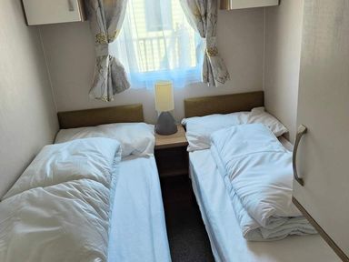 A bedroom with two beds and a lamp on a bedside table at Clarach Bay Holiday Village W18 Aberystwyth