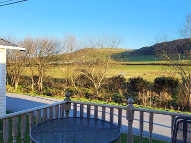 A view from a deck with a table and chairs overlooking a field at Clarach Bay Holiday Village W18 Aberystwyth