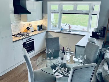 A kitchen with a round dining table and chairs at O7 in Abersoch