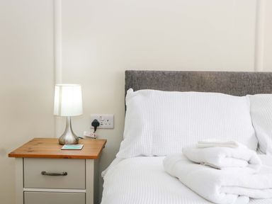 A bedroom with a bed, lamp, and nightstand at Halsdon Avenue Exmouth