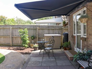 A garden with a table and chairs under an awning at Halsdon Avenue Exmouth