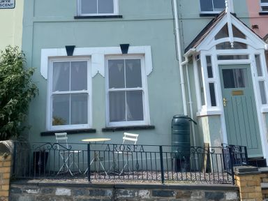 A table and chairs outside a house with a green door at Arosfa in New Quay