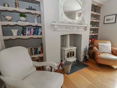 A living room with a bookshelf and a fireplace at Arosfa New Quay