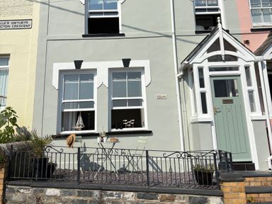An outdoor area with a table and chair in front of a house at Arosfa in New Quay