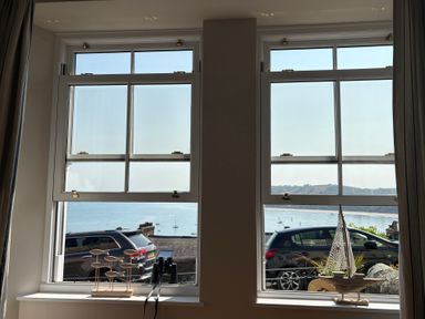 Two windows with ocean view and decorative items in a living room at Arosfa New Quay