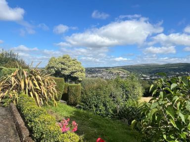 A garden with flowers and trees overlooking a valley at The White House Okehampton