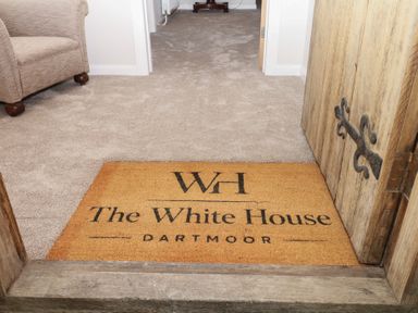 A hallway with a door mat and a couch at The White House Okehampton