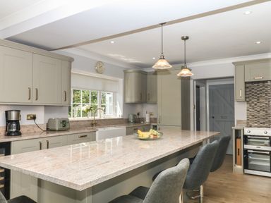 A kitchen with cabinets, island, appliances and stools at The White House in Okehampton