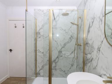 A bathroom with a shower and marble walls at The White House in Okehampton