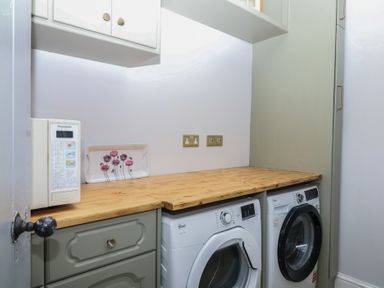 A laundry room with a washing machine, tumble dryer, and countertop at The White House in Okehampton