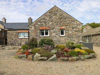 A stone house with garden and seating area at The Old Dairy near Solva