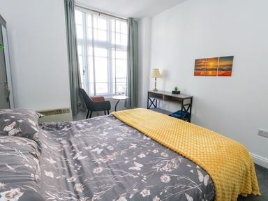 A bedroom with a bed and a table at Ocean Breeze in Weymouth