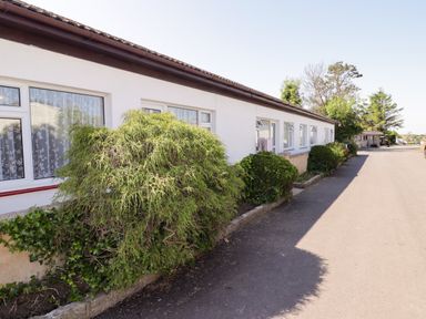 A pathway alongside a building with bushes at Cottage 1 Tenby