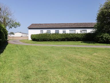 An outdoor view of a house surrounded by grass and hedges at Cottage 3 in Tenby