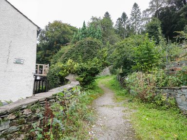 A path beside a stone wall and plants at Flat 4 Grasmere Lodge Ambleside