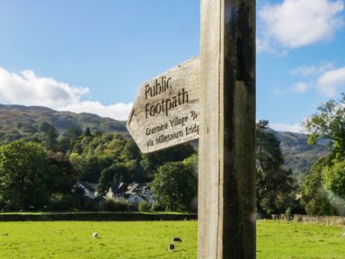A signpost indicating public footpath to Grasmere Village via Millennium Bridge