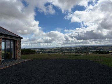 A house with clouds and fields in the background at High View Barn Launceston