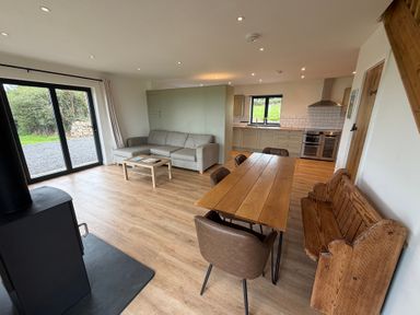 A living room with a dining table and kitchen area at High View Barn in Launceston