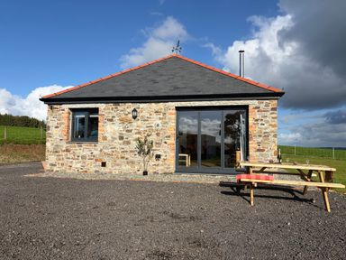 A stone building with a table and benches at High View Barn Launceston