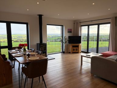 A living room with a dining area and large windows at High View Barn Launceston