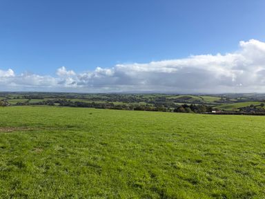 An open field with grass and hills under a blue sky at High View Barn Launceston
