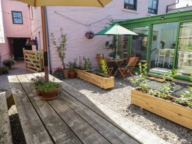 A garden with wooden furniture and plants at 11b Market Street Narberth