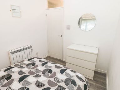 A bedroom with a bed, chest of drawers and a mirror at Coedrath Park