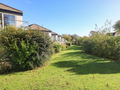 A garden pathway with bushes and buildings at Coedrath Park
