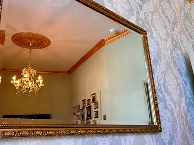 A mirror reflecting a chandelier and wall photos at Downton I in Alnwick