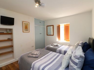 A bedroom with two beds, a television, and a wardrobe at Scoops' Nook in Caernarfon