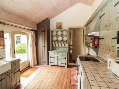A kitchen with a sink, cupboards, and plates on display at The Coach House Cottage BALLYCOMMON