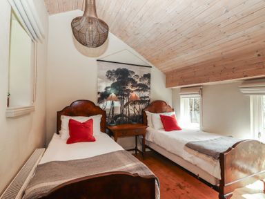 A bedroom with two beds and a table at The Coach House Cottage BALLYCOMMON