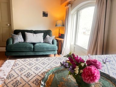 A living room with a green sofa and flowers on a table at The Coach House Cottage Ballycommon