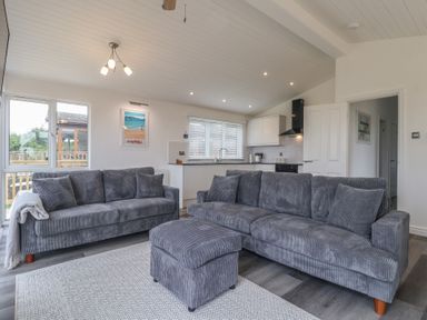 A living room with sofas and a kitchen area at Lodge 19 in Torpoint