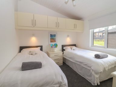 A bedroom with twin beds and a window at Lodge 19 in Torpoint