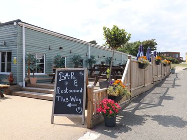 An outdoor area with a sign for the bar and restaurant at Lodge 19 in Torpoint