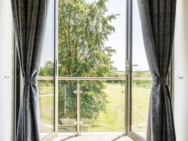 A balcony with glass doors and view of trees at Cotswolds Apartment, sleeps 4 in Chipping Norton