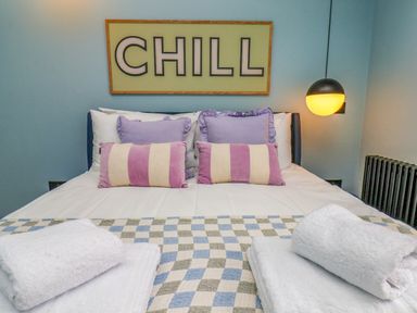 A bedroom with a bed, pillows, towels, and a light fixture at Apartment Blue in Whitby