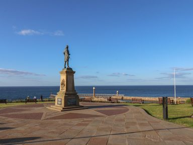 An outdoor area with a statue and benches overlooking the sea at Apartment Green in Whitby