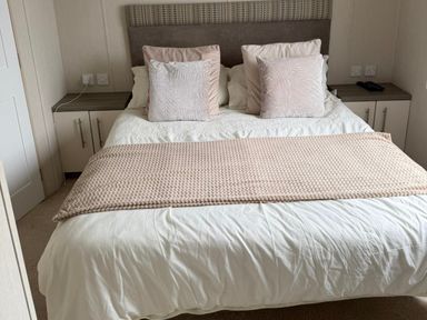 A bed with pillows and a bedside table at Trecco Bay holiday park, Porthcawl