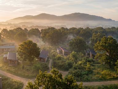 A view of cabins surrounded by trees with hills in the background at Arbora 1.0 (Pet) in Malvern