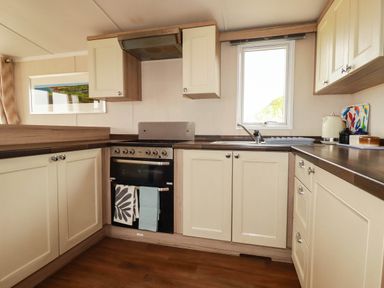 A kitchen with cabinets, oven, sink and window at Roslenn St Agnes