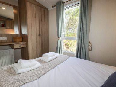 A bedroom with a bed and towels on the side at Roslenn in St Agnes
