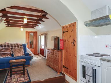 A living room with a sofa and kitchen area at Moorland Retreat in Bodmin