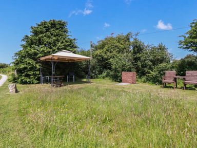 A garden with a table and chairs under a canopy at Moorland Retreat in Bodmin