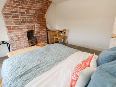 A bedroom with a bed and desk against a brick wall at The Watch House in Weymouth