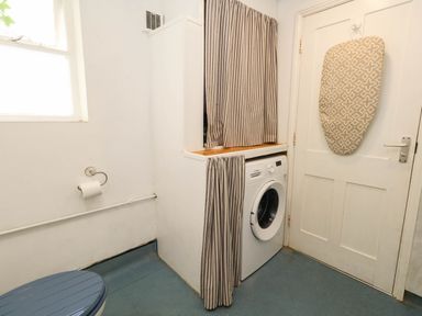 A laundry room with a toilet and washing machine at The Watch House in Weymouth